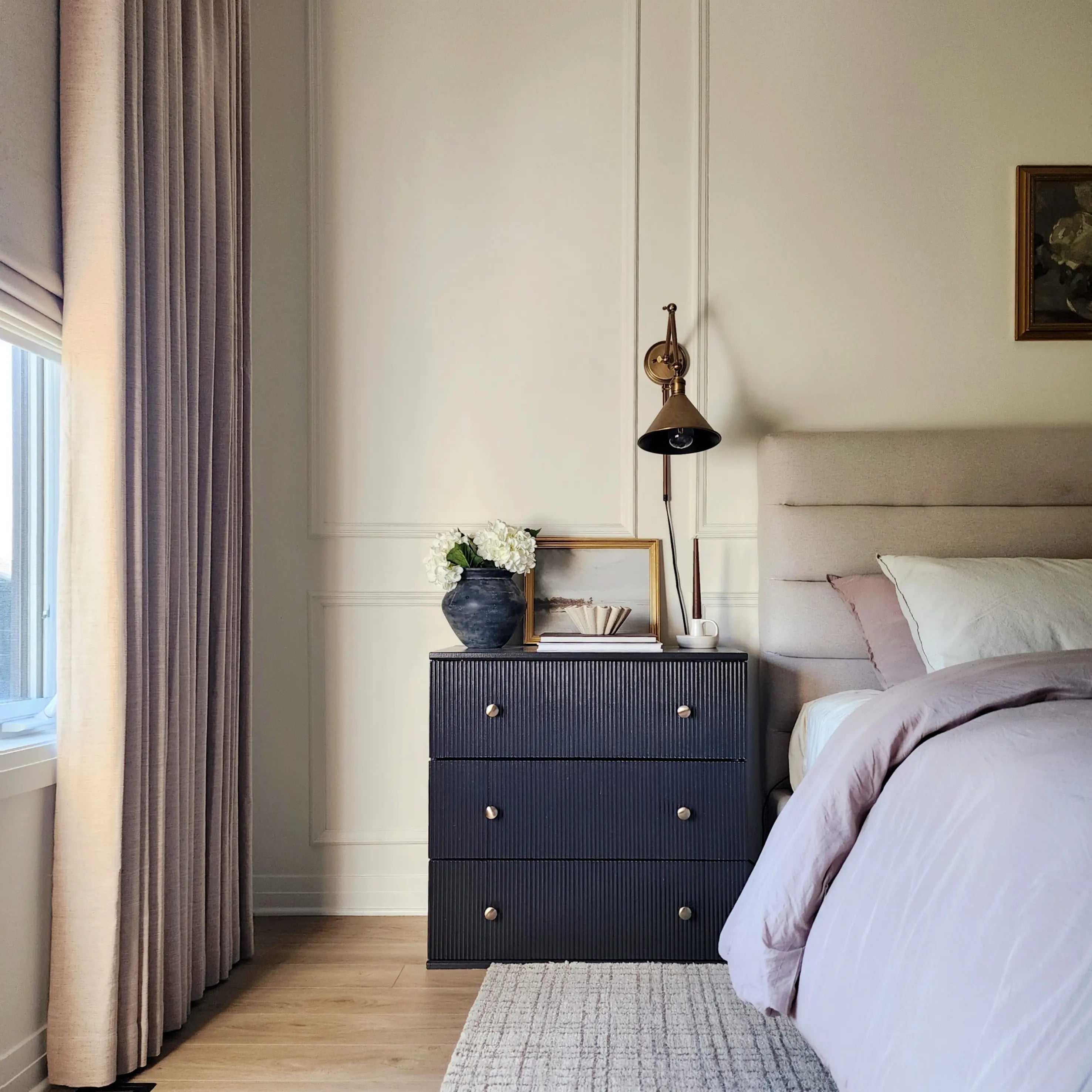 Pleated curtains in a soft neutral tone frame the window, adding texture and elegance to the modern bedroom decor