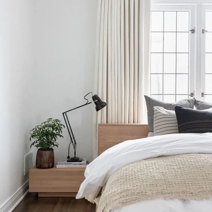 Cozy neutral bedroom with soft bedding, elegant drapery, and minimalist decor.