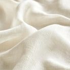 Close-up of beige linen fabric drapery sample, showing its soft texture and smooth folds.