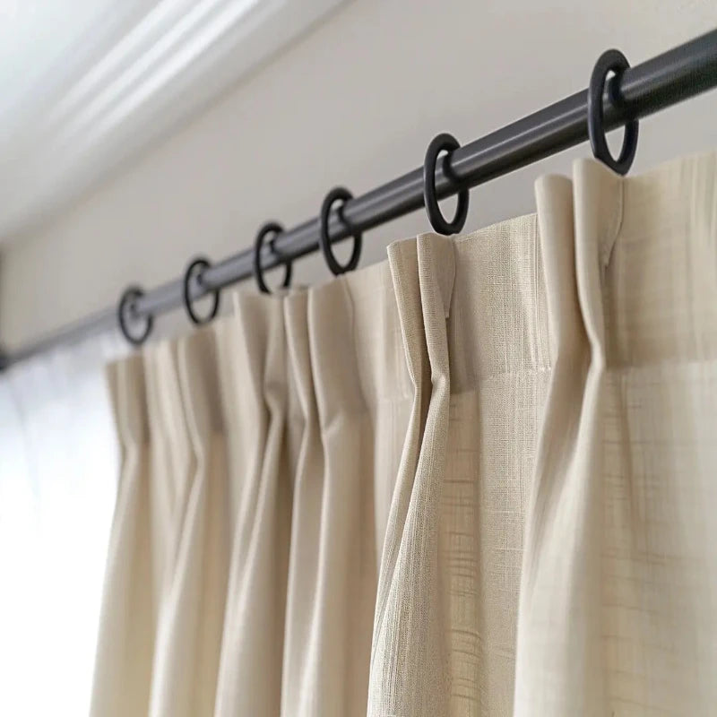 Close-up of drapery Rods on a curtain rod with pleated beige fabric