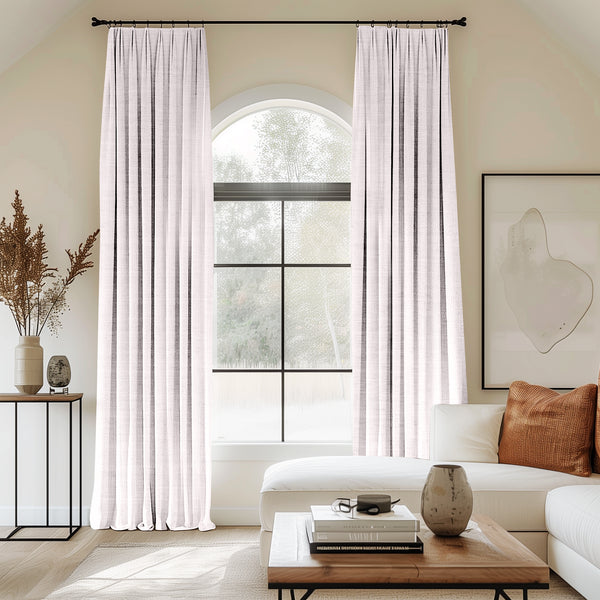 Living room with arched window and white velvet pleated curtains.