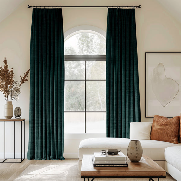 Living room with arched window and dark green velvet pleated curtains.