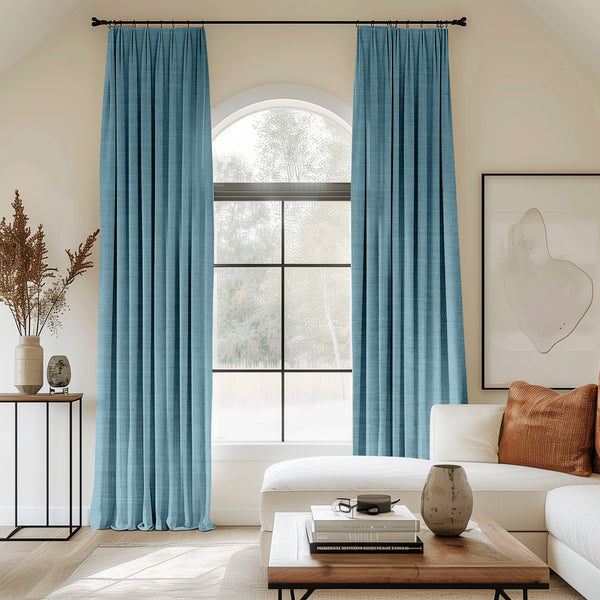 Living room with arched window and turquoise velvet pleated curtains.