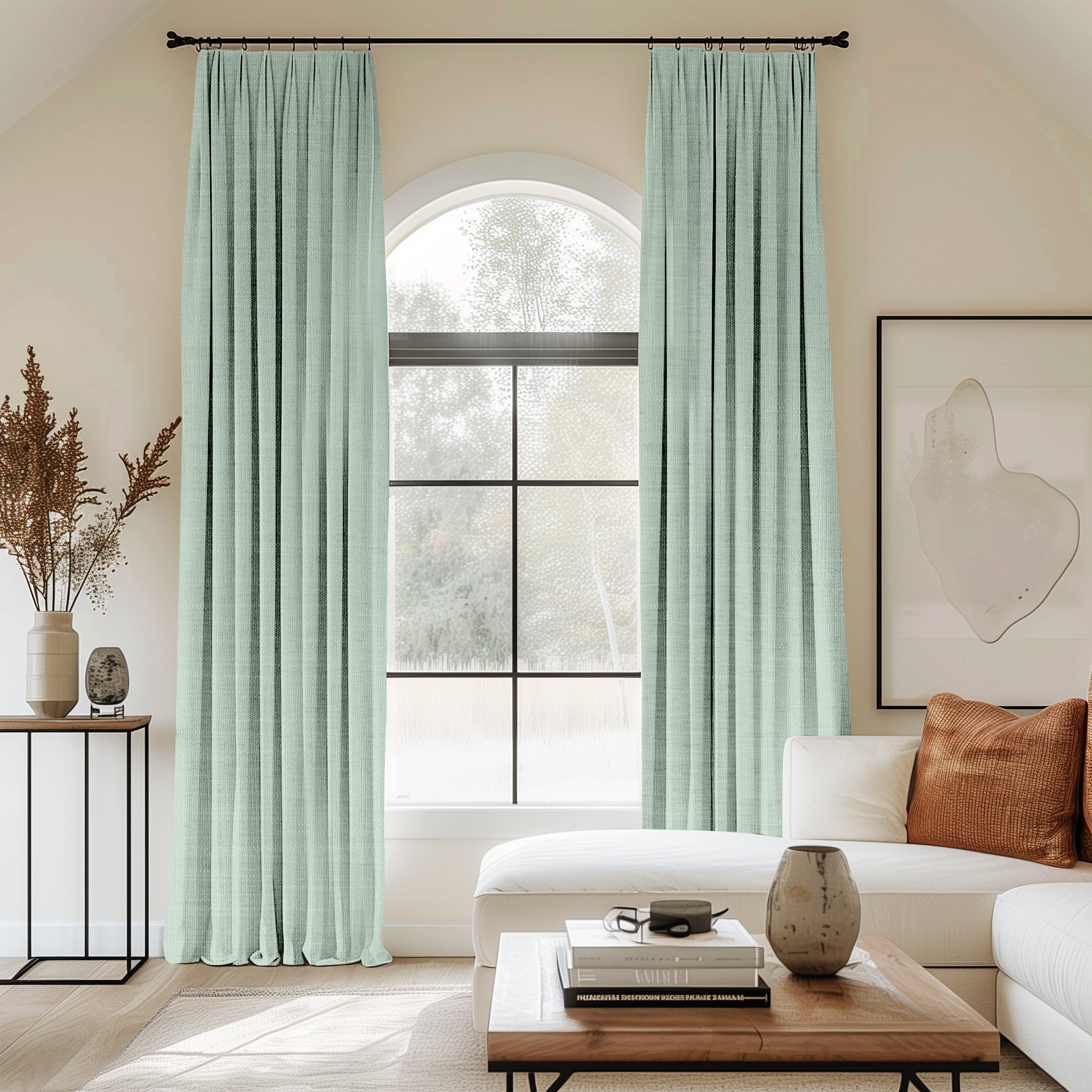 Living room with arched window and mint green velvet pleated curtains.