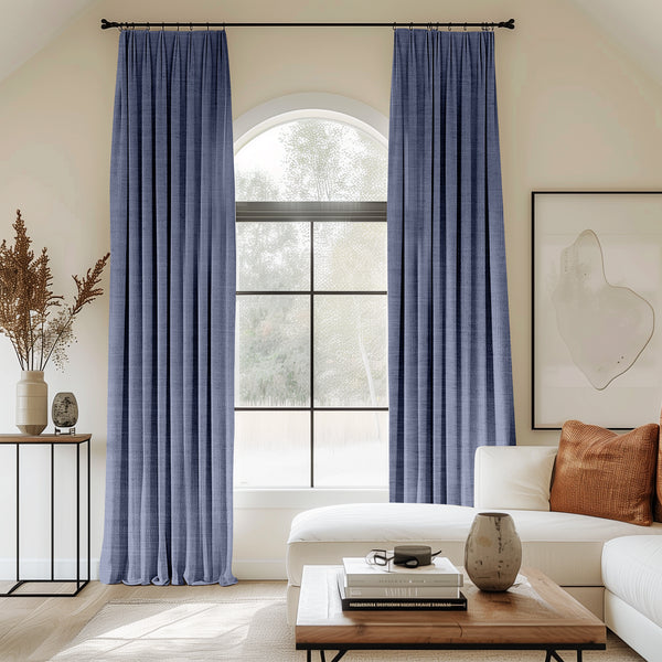 Living room with arched window and periwinkle velvet pleated curtains.