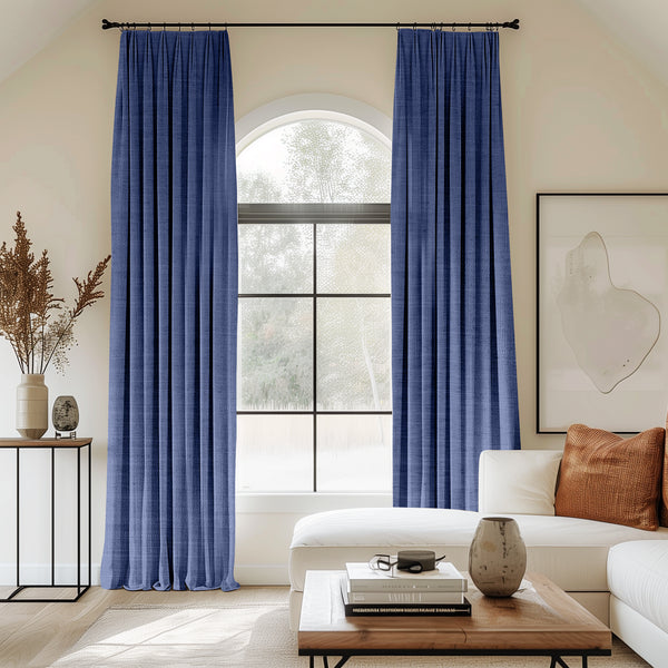 Living room with arched window and royal blue velvet pleated curtains.