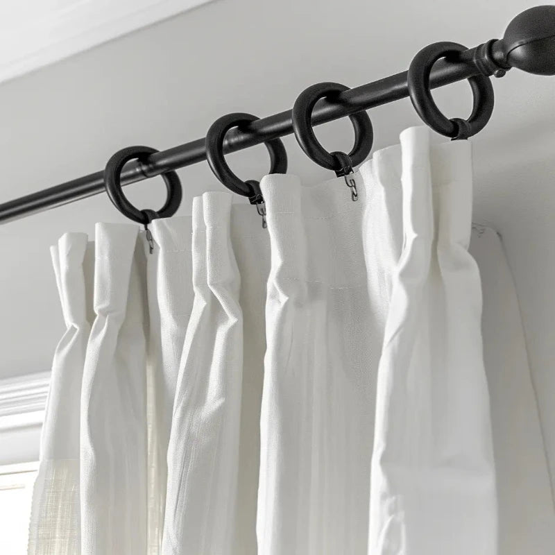 Close-up of drapery hooks and accessories on a black curtain rod with white pleated curtains.