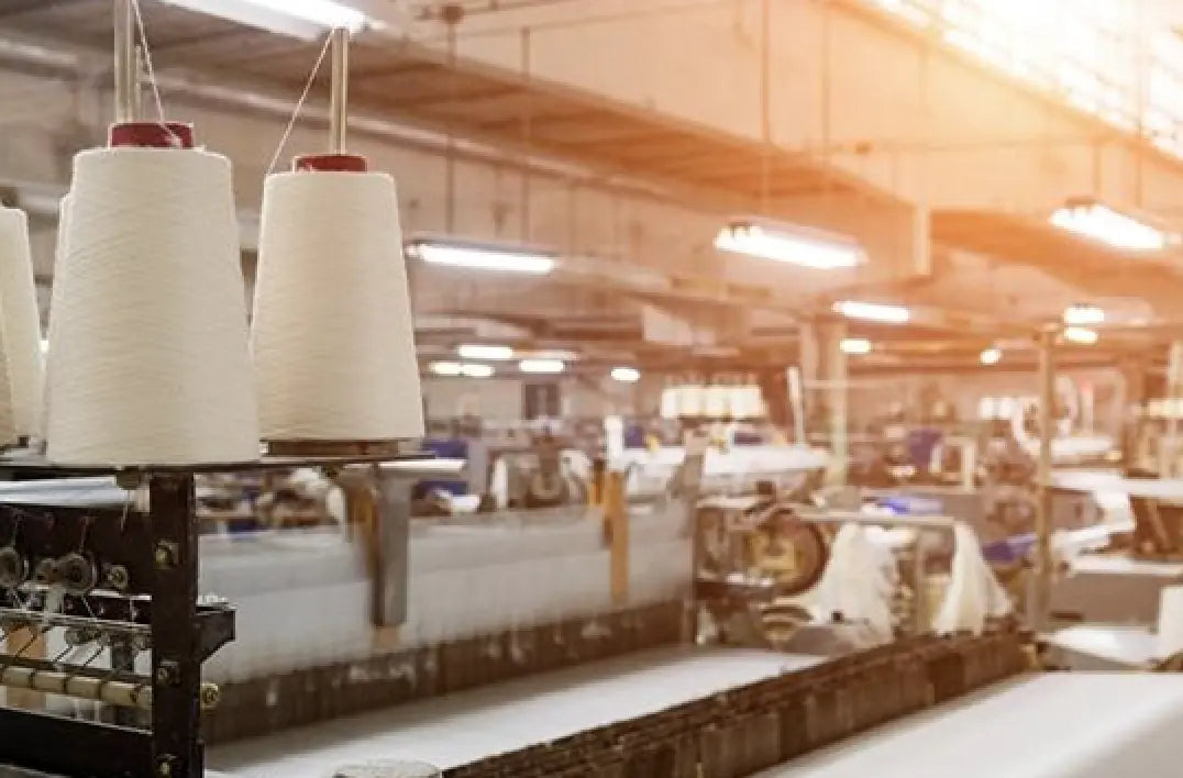 Textile factory with yarn spools and machinery, representing a fabric producer.