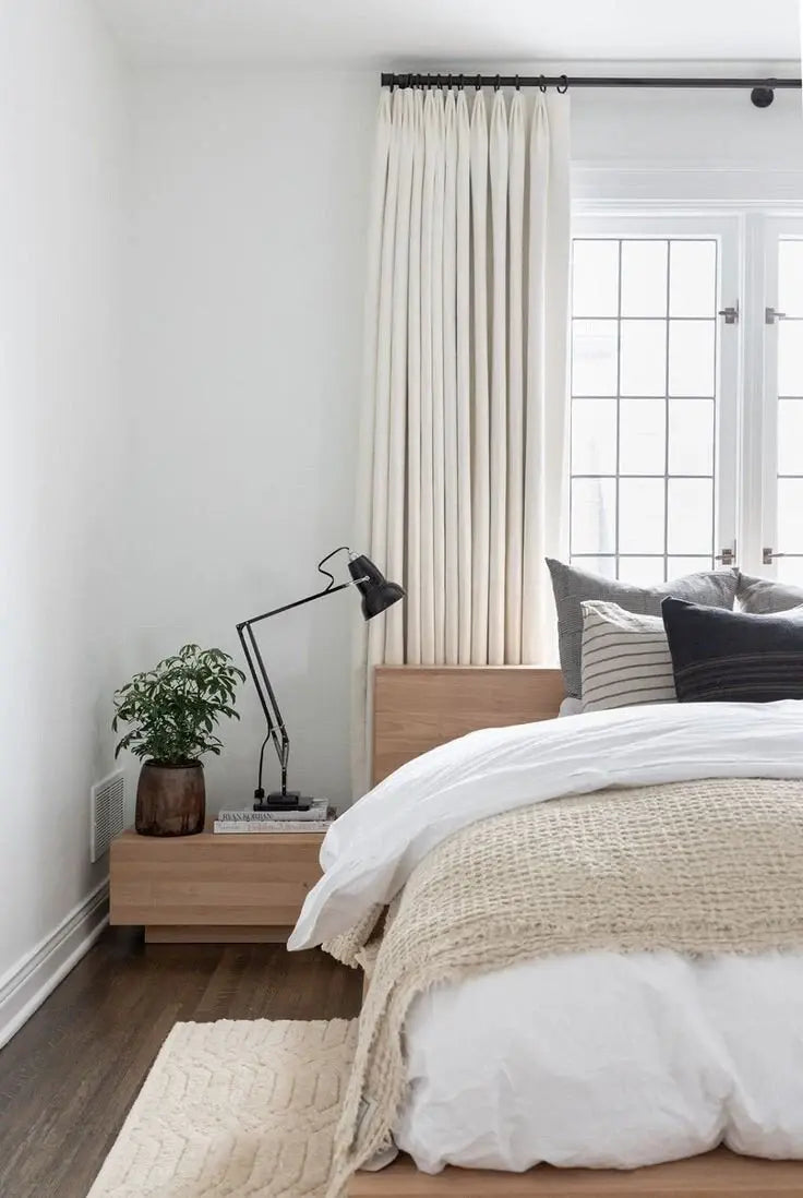 Cozy neutral bedroom with soft bedding, elegant drapery, and minimalist decor.