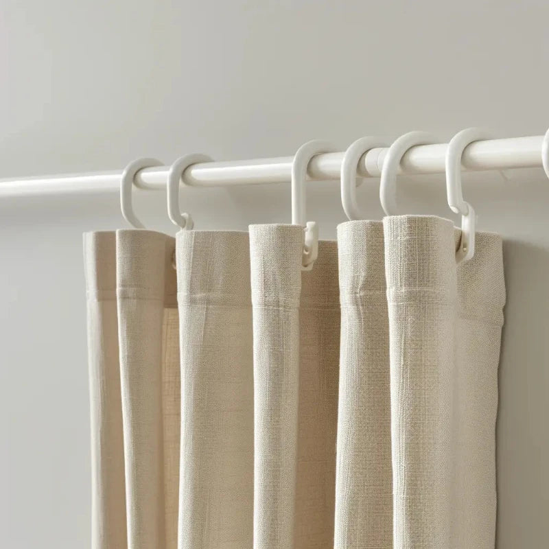 Beige curtains hanging from white curtain rings on a matching rod