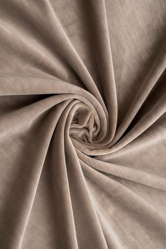 Elegant velvet fabric in a soft beige tone, beautifully draped in folds showcasing luxurious texture and sophistication.